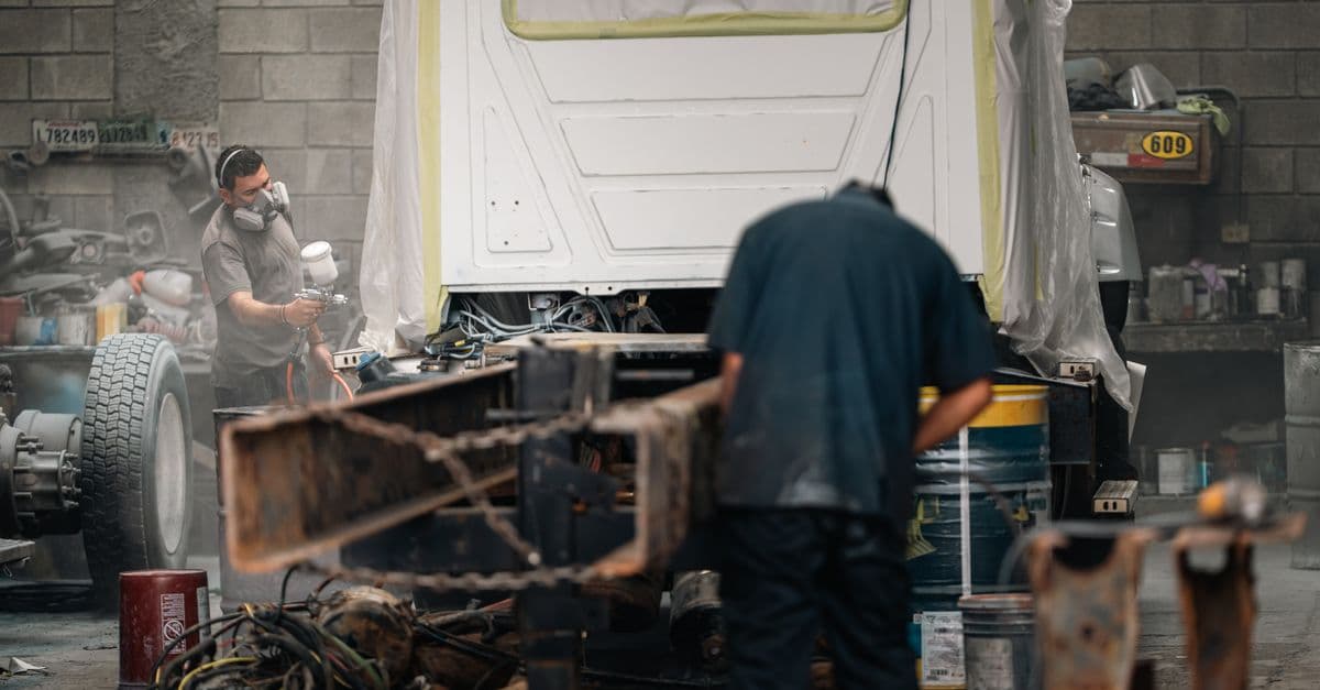 Spray painting a masked vehicle cab in a workshop